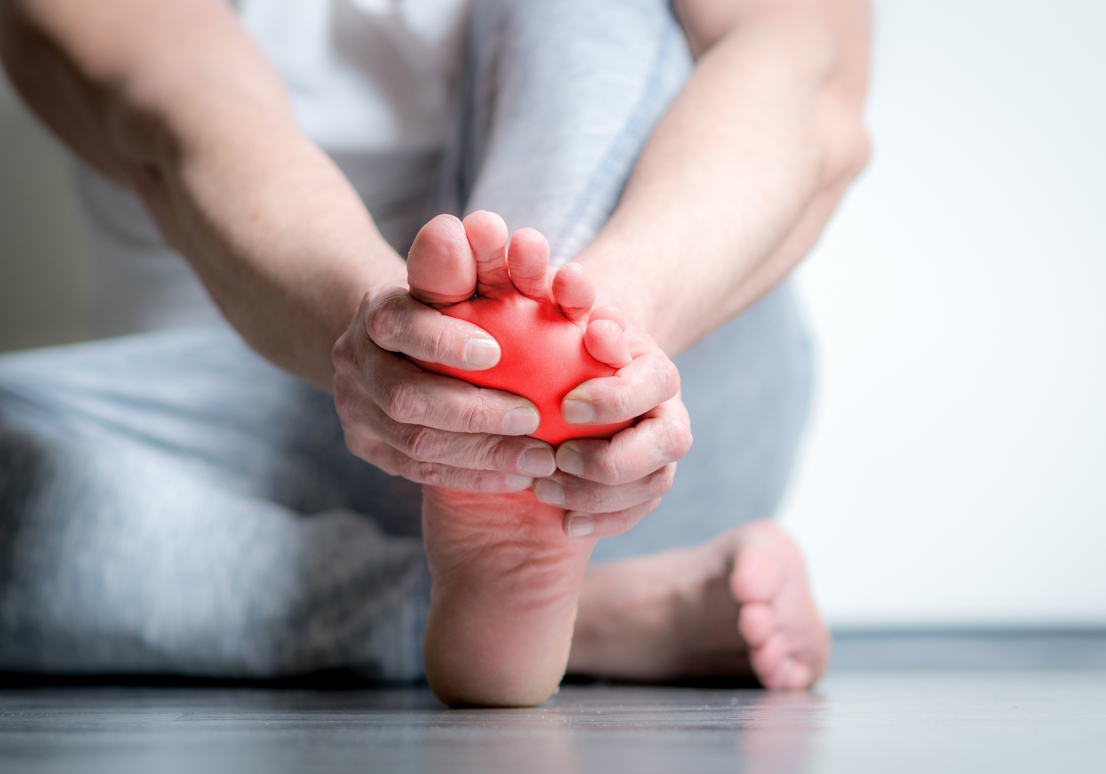 Homme qui se tient l'avant du pied entre ses mains et qui a mal